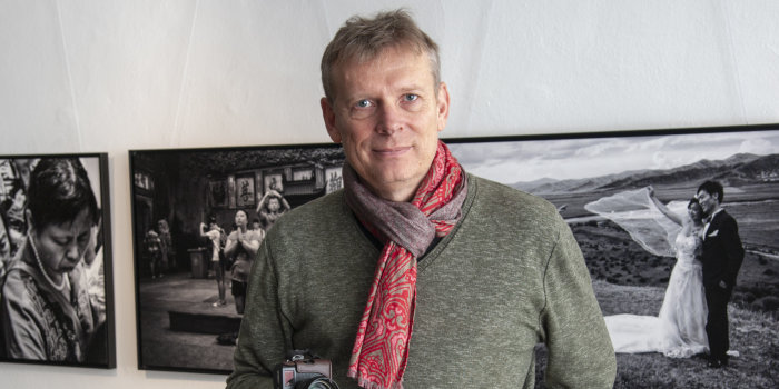 Ein Mann mit Kamera steht vor schwarz-weiß Fotos