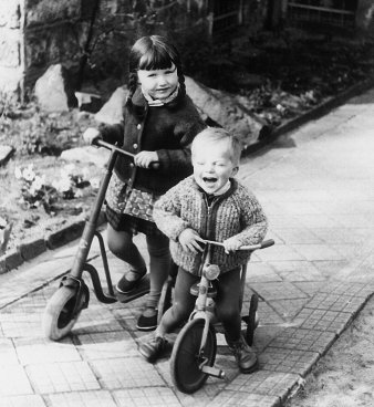 Zwei Kinder mit Roller und Dreirad.