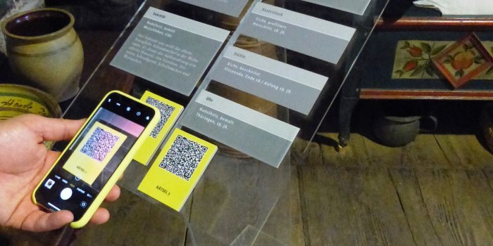 Ein Handy scannt einen Code von einer Ausstellungstafel