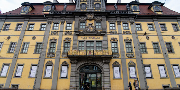 Verziertes gelbes Gebäude mit weißen Bannern in den Fenstern im Erdgeschoss