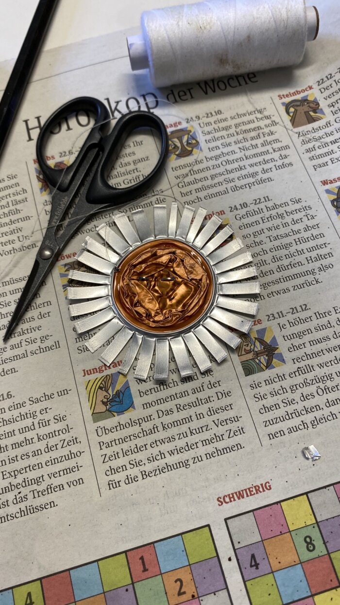 Upcycling Faden, Schere, Zeitung und zu einer Blume geschnitten Kaffeekapsel