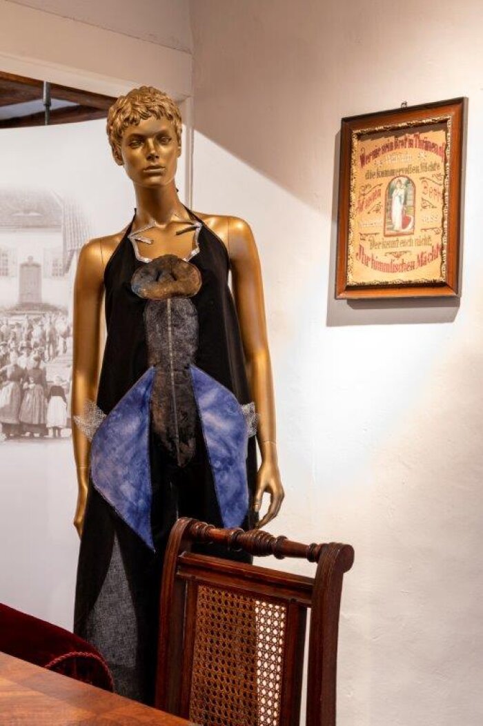 Schürze Textilinsekten Goldne Figur mit schwarzer Schürze