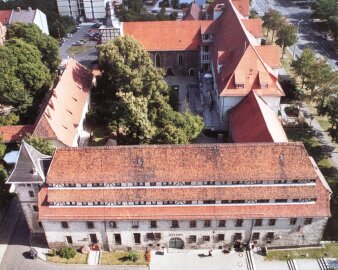 Historischer Gebäudekomplex mit Kirche und Innenhof mit Bäumen
