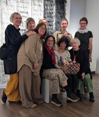 Neun lächelnde Frauen mittleren Alters mit einem Präsentkorb