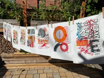 Gedruckte Kunstwerke in bunten Farben mit Klammern an einer Wäscheleine hängend
