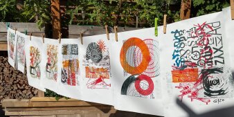 Gedruckte Kunstwerke in bunten Farben mit Klammern an einer Wäscheleine hängend