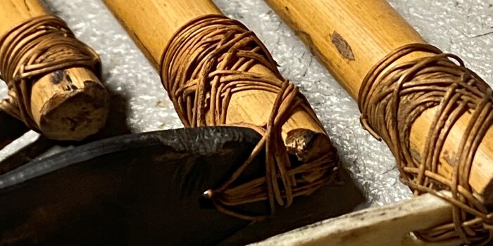 Detailansicht eines Tatauiersets bestehend aus drei kleinen Bambusstangen die mit Bastkordel umwickelt
