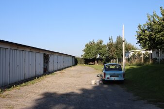 ein Trabant steht an einer Garagenanlage