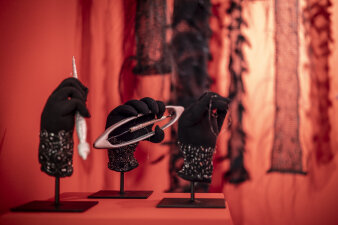 drei schwarze Handfiguren halten verschiedene Utensilien zum Umngang mit Textilien