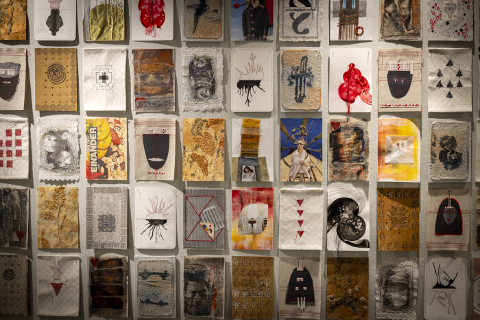 zahlreiche farbig gestaltete und teils bestickte Karten hängen an einer Wand