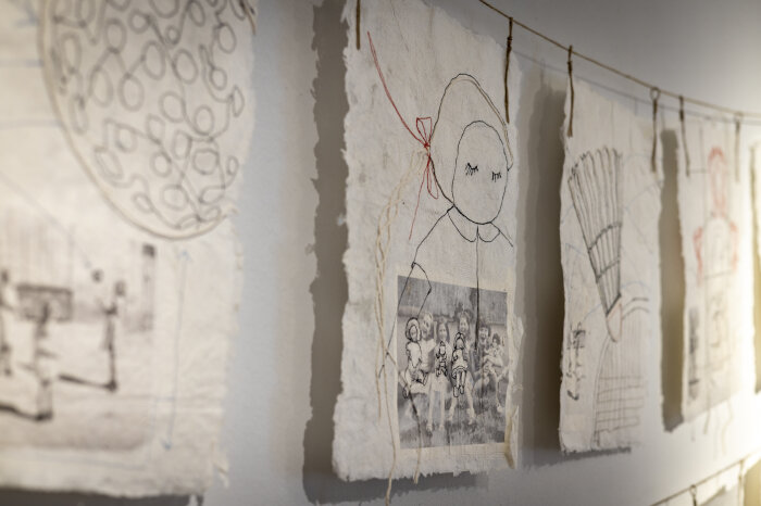 Kindheitsspiele - Ute Herre Werke mit Fäden auf handgeschöpftem Papier an einer Wand hängend