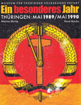 Titel und Abbildung einer veränderten DDR-Fahne. Ehrenkranz, Hammer und Zirkel stellen eine Uhr 5 vor 12 dar