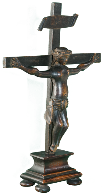 Kleines Kruzifix mit vereinfachter Jesusfigur etwa 30 cm hoch stehend auf Unterbau mit vier gequetschten Kugelfüßen